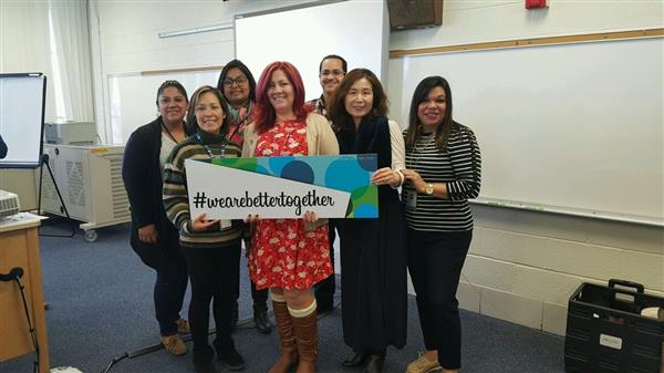 A group of people proudly displaying a sign for an educational event or program.