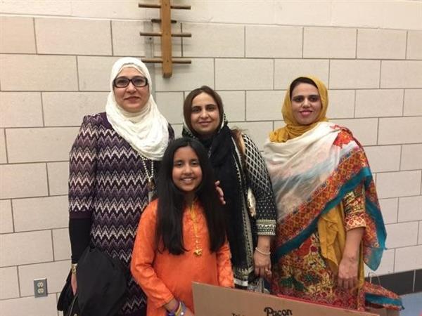 A group of women dressed in traditional South Asian attire, posing together for a photo.