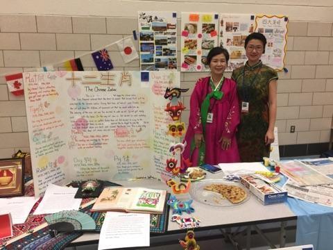 Two women standing next to a table filled with items and posters, posing for the camera.