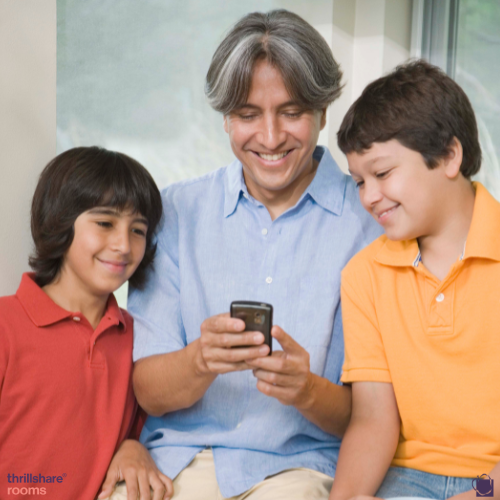 dad looking at a cell phone with his two sons