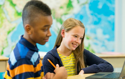 Two students working at a laptop with a world map in the background