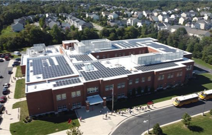 Wide exterior photo of a school with neighborhoods in the background