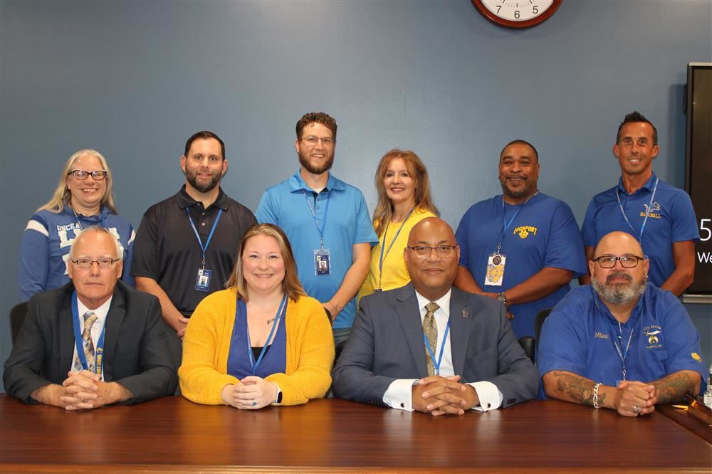 10 School board members smiling all together in a room