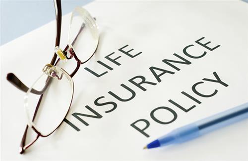 Text says "Life Insurance Policy" on a sheet of paper with glasses on top of it