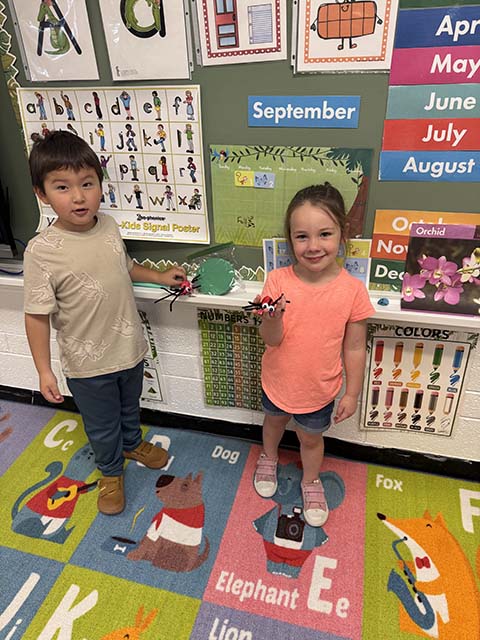 Students pose with ants they've crafted.
