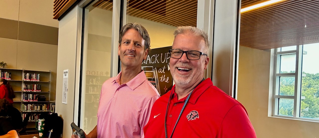Two male teachers smiling in library