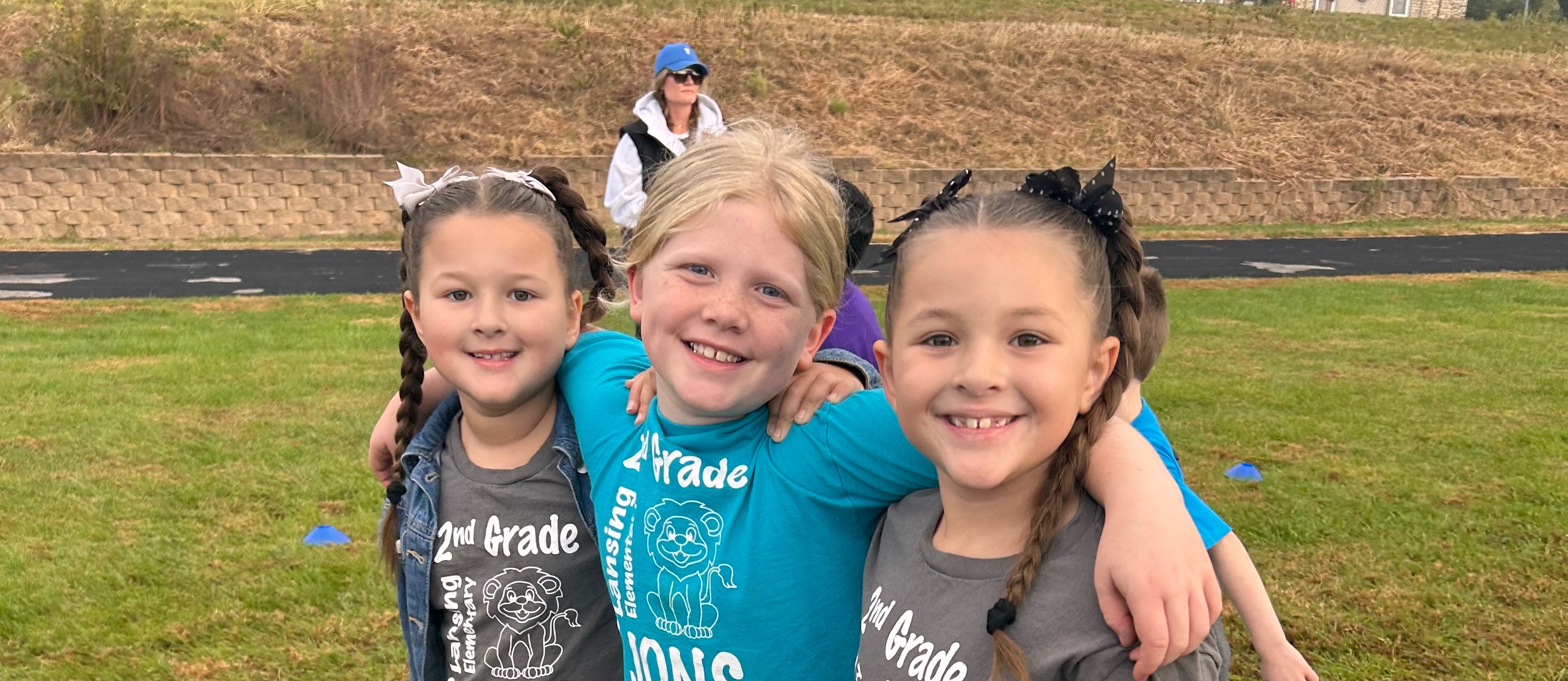 Three girls outside on a playground with their arms around each other
