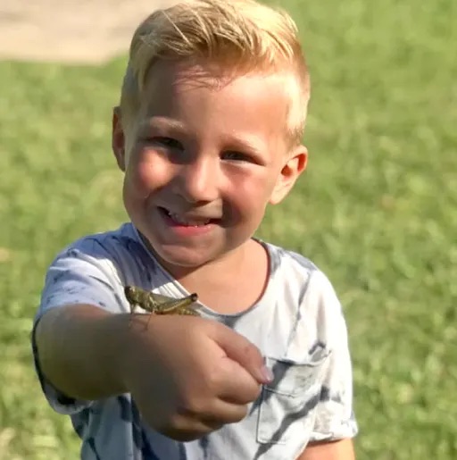 boy holding a cricket in his hand