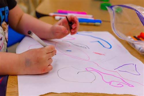 Student drawing on paper with markers