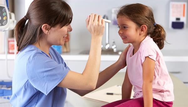 School nurse checking little girl's eyes
