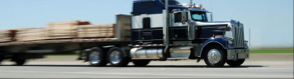 semi truck driving down interstate hauling lumber