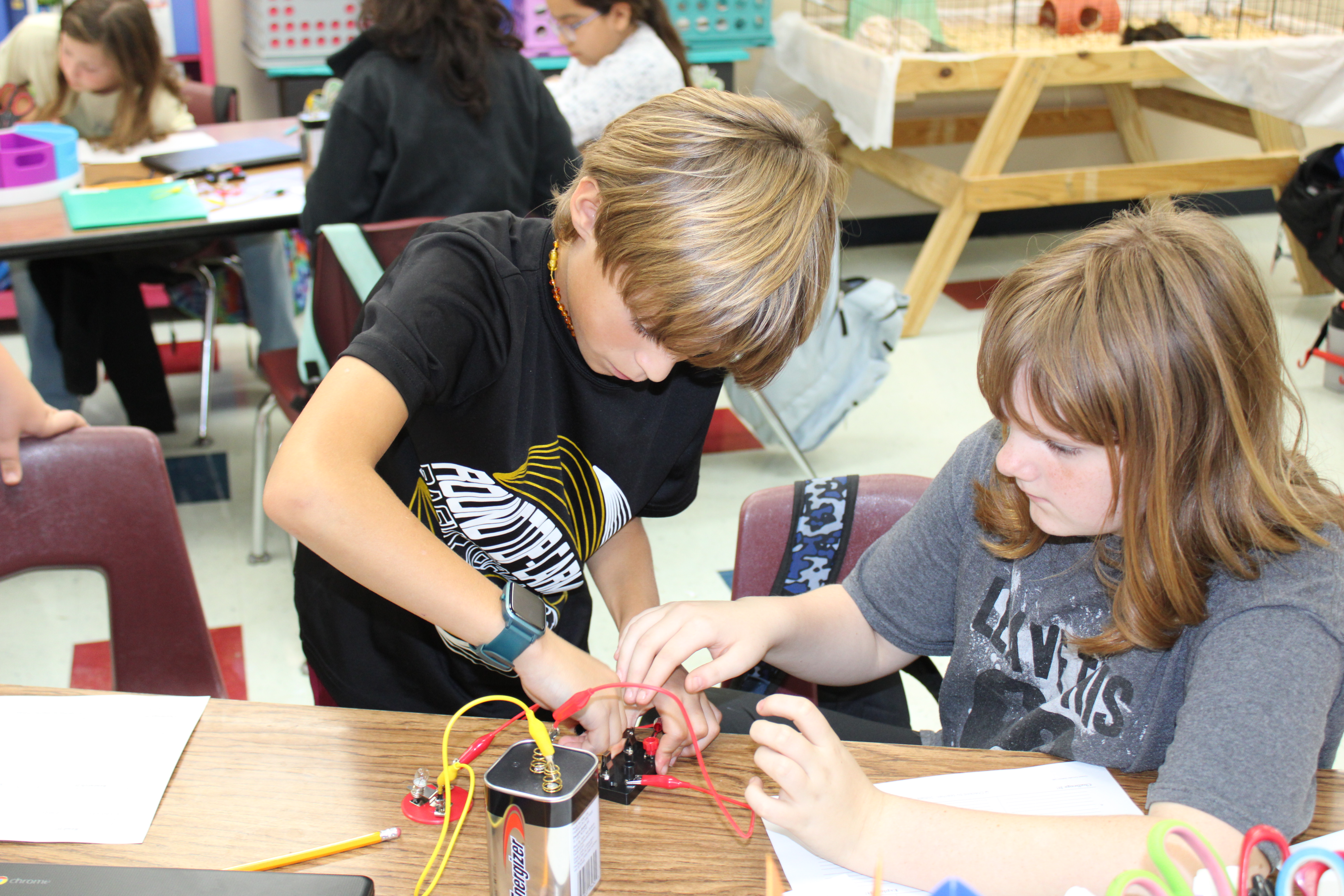 Two students connecting cable to a battery