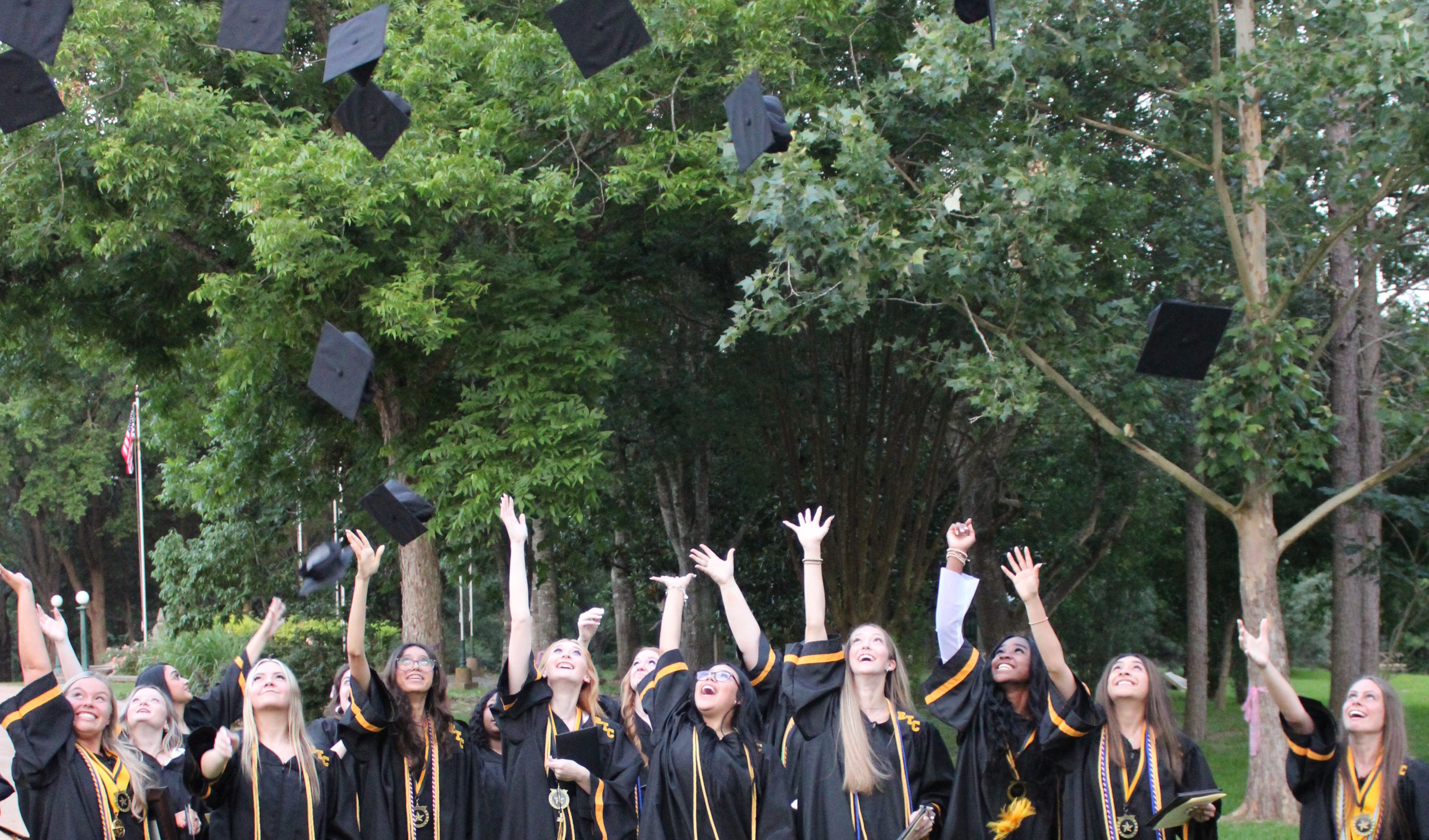 Students in graduation gowns throwing caps