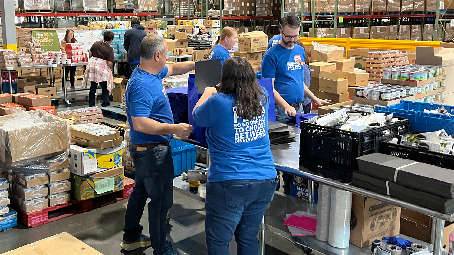 Three individuals working together in a warehouse setting, sorting and handling various items on shelves.