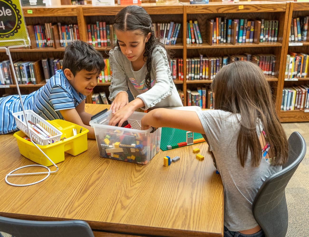 3 kids sitting playing with toys on a table