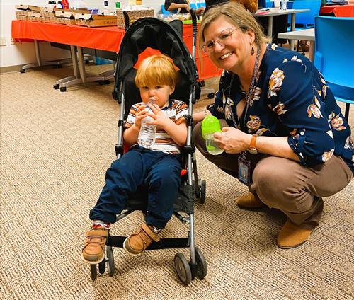 staff member next to a little kid on a stroller   