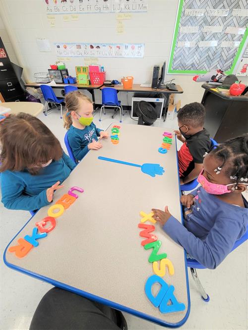 4 students sitting and doing an activity on a desk