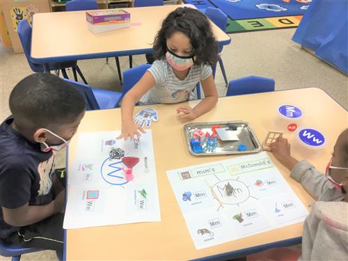 3 students sitting and doing an activity on a desk