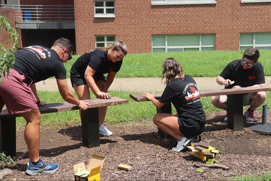 volunteers cleaning up and repairing benches at school
