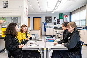 4 students talking on a classroom