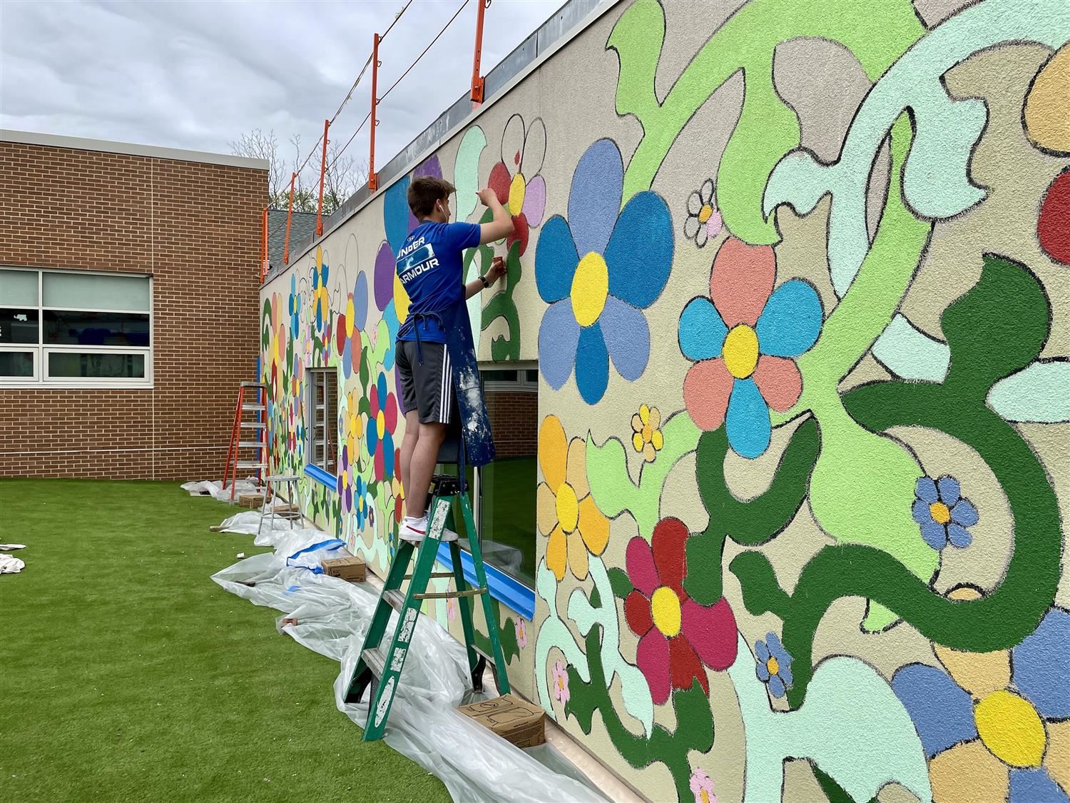 student painting art on the wall with flowers and plants