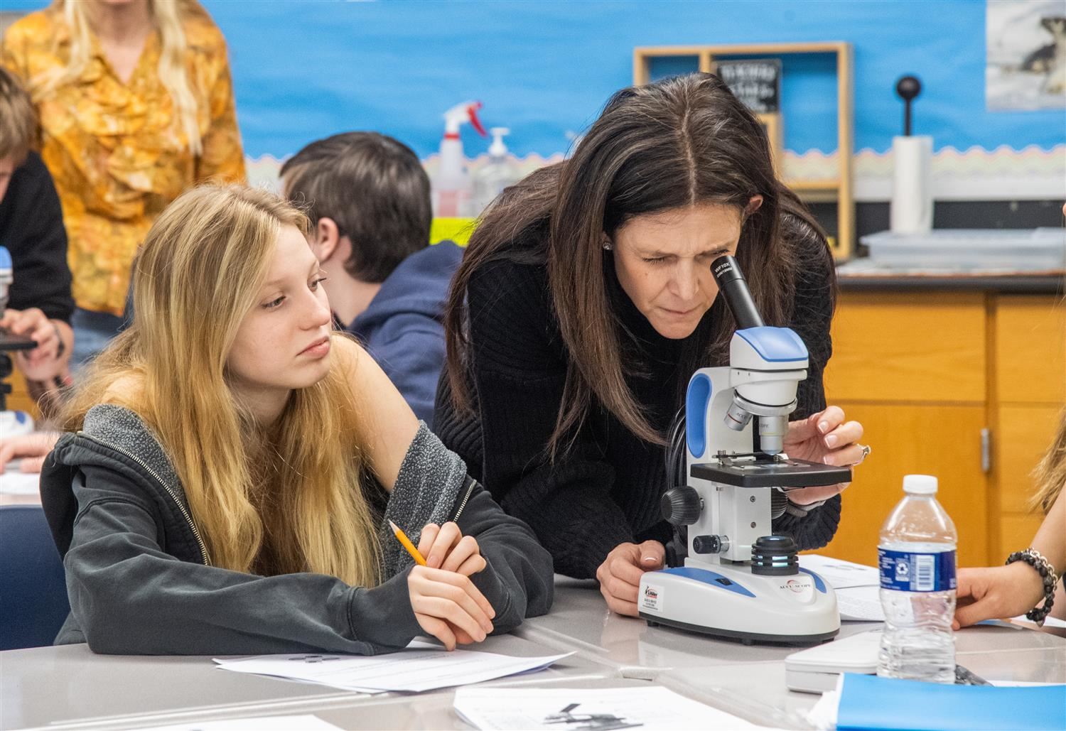 teacher looking through a microscope with a student