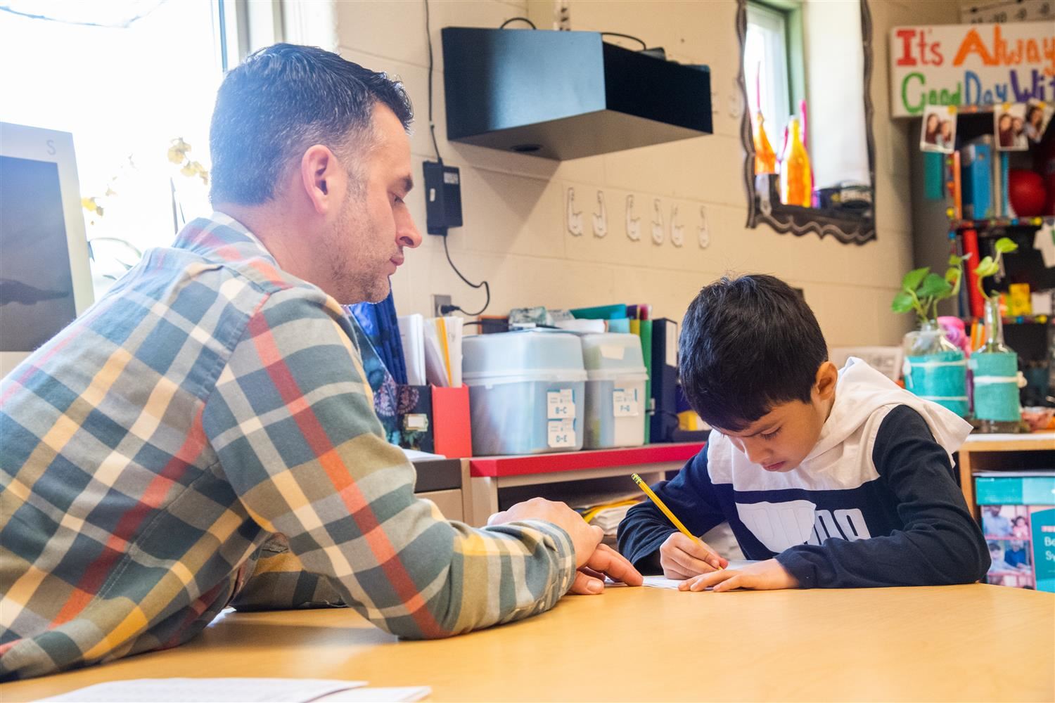 teacher looking at a student while he is writing