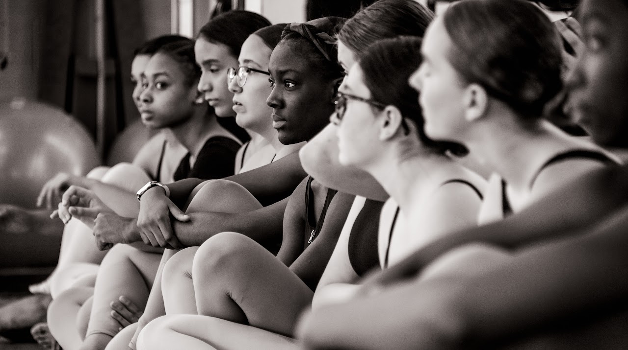 Black and white photo of the dance team sitting on the floor 