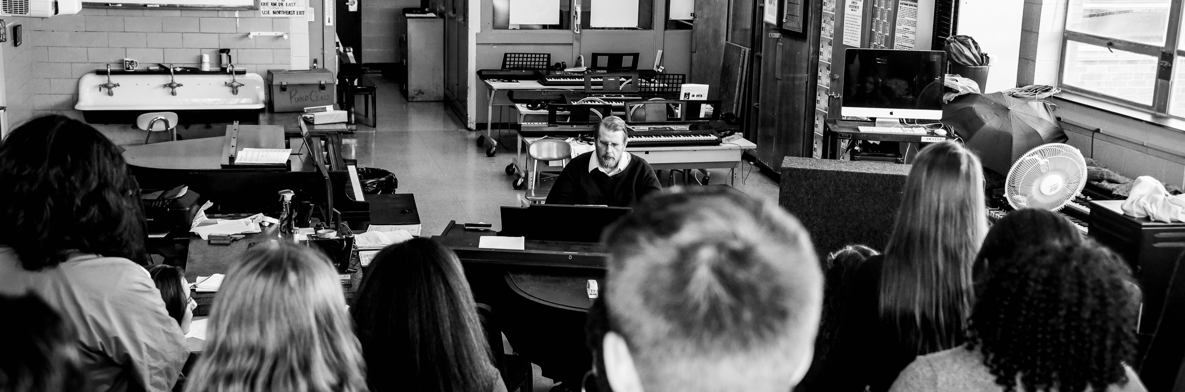 Music teacher playing piano in front of the class.