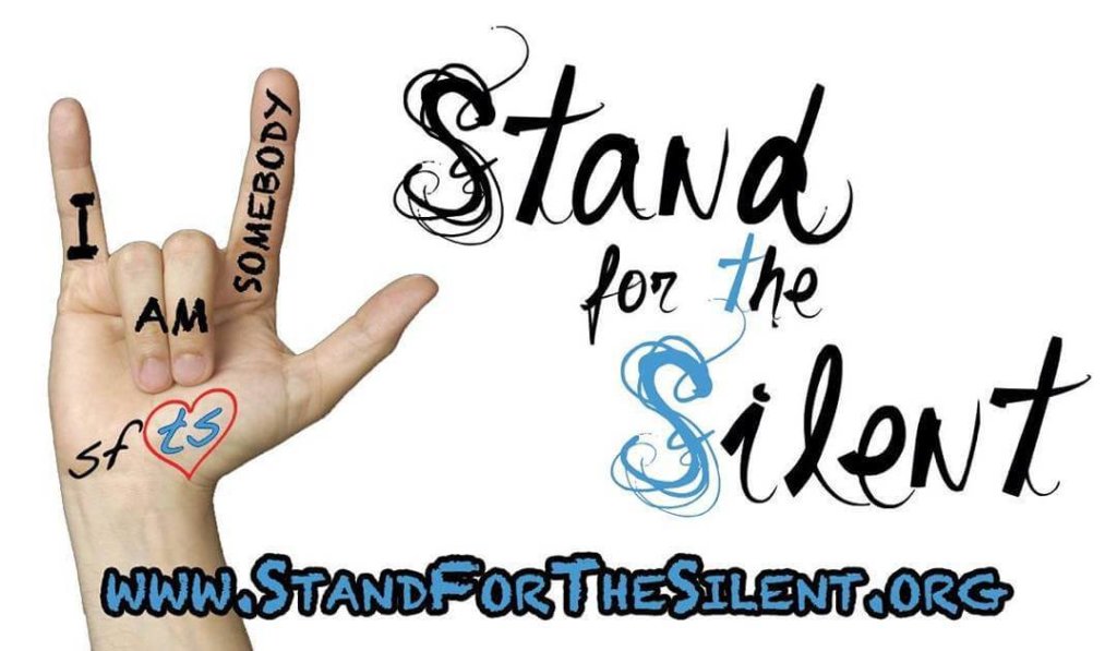 ext on a whiteboard that reads: "Stand for the Silent." There is also a small cartoon illustration of a person with their hand raised.