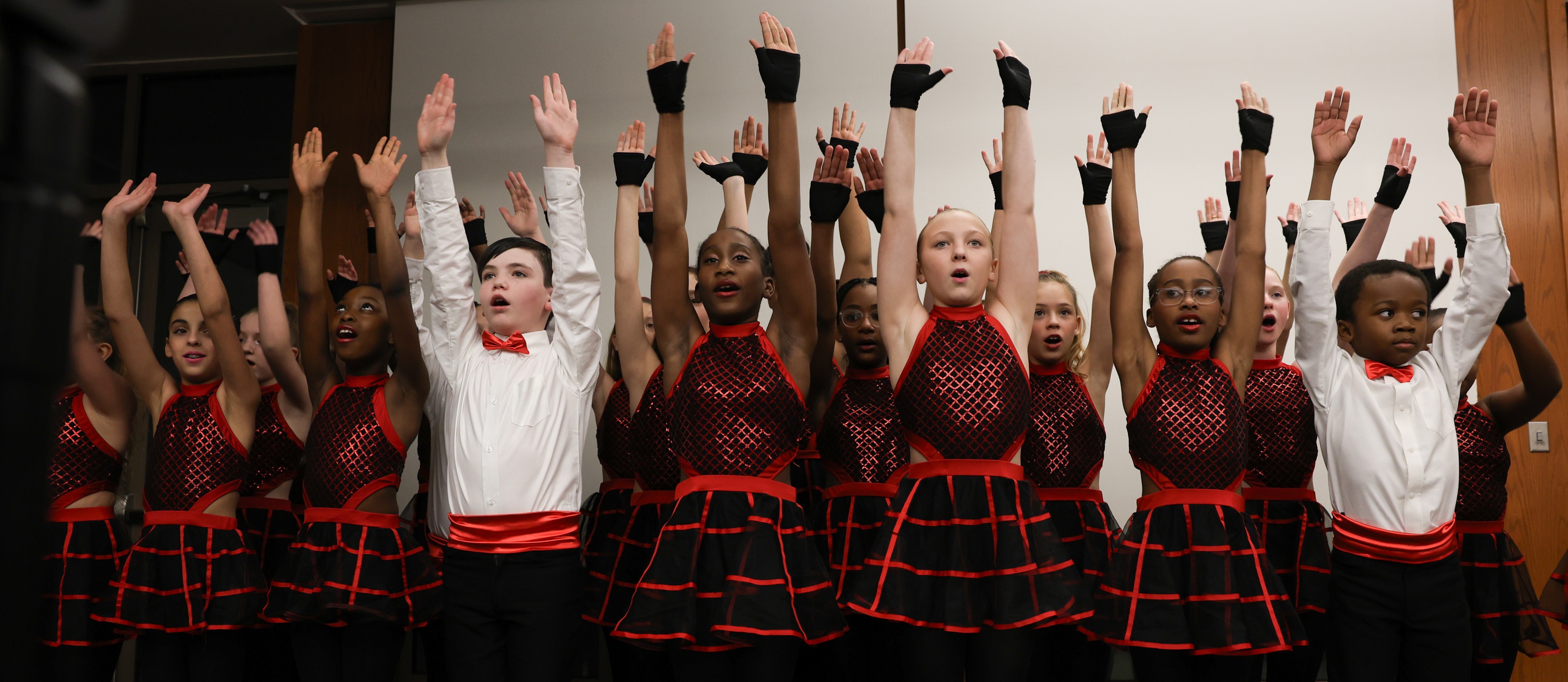 A group of students perform in black and red uniforms.