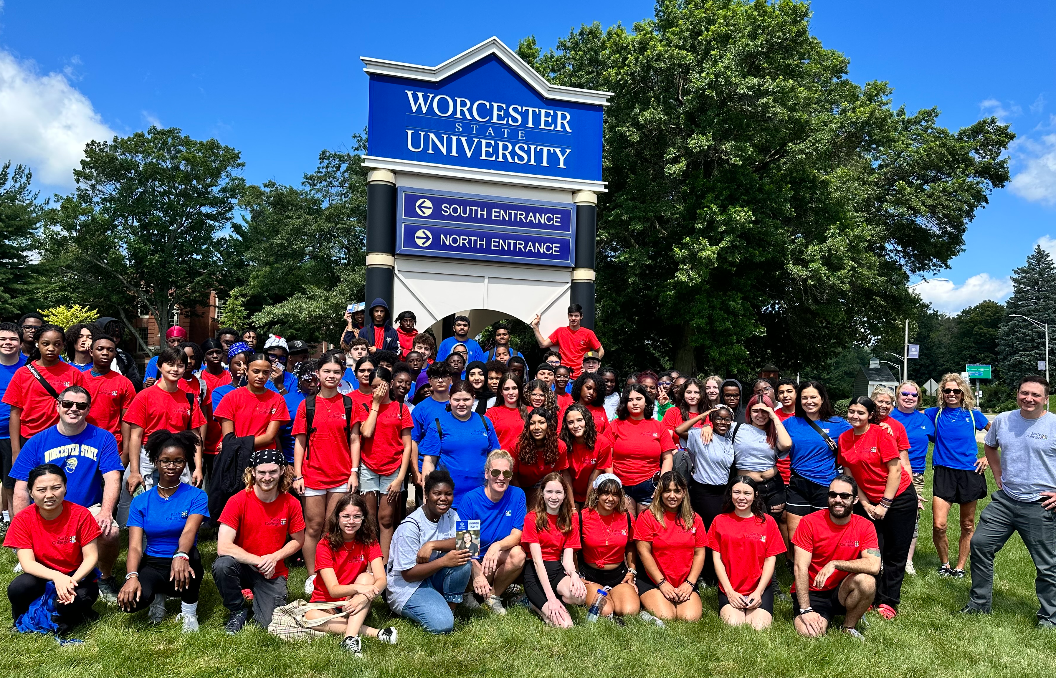 A large group of students standing in front of the Worcester State University sign