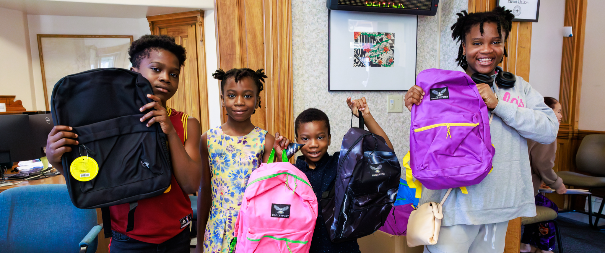 Four siblings hold up backpacks.