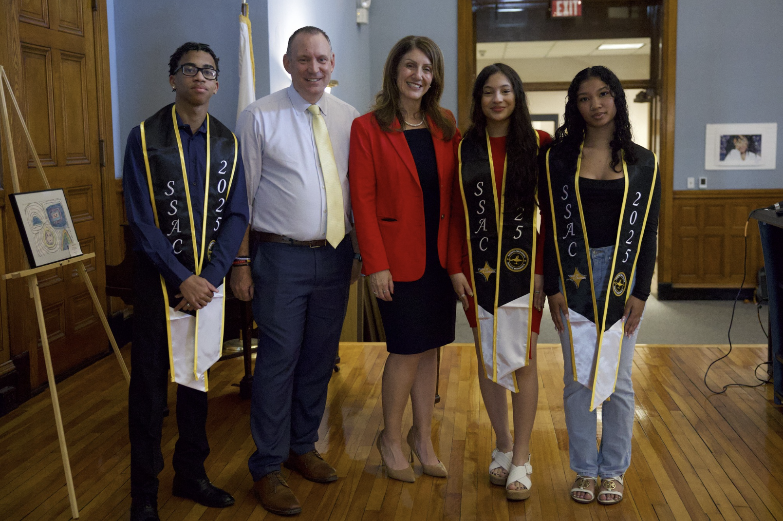 Three students pose for a photo with Brian Allen and Rachel Monárrez