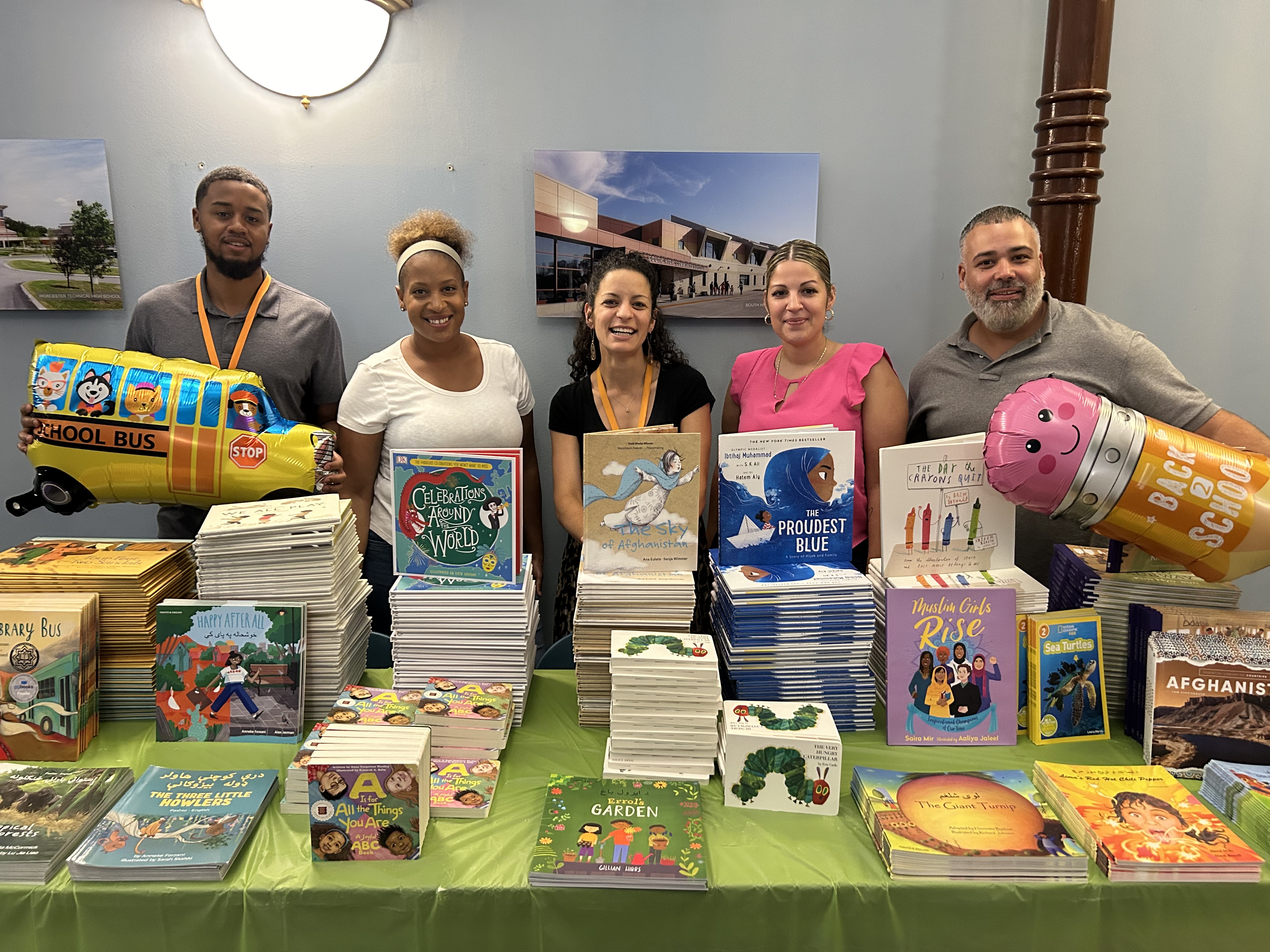 Five adults behind a table with children's books