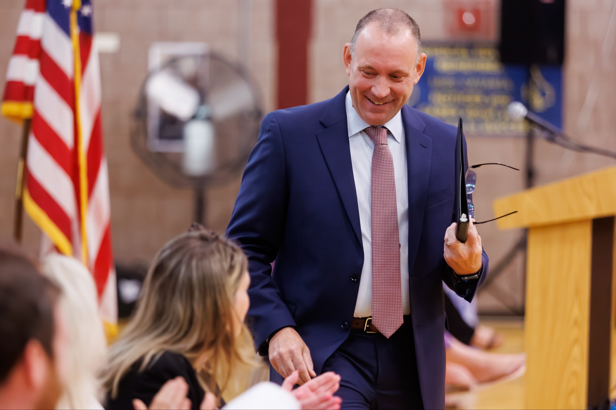 Brian Allen speaking to a teacher in a school auditorium