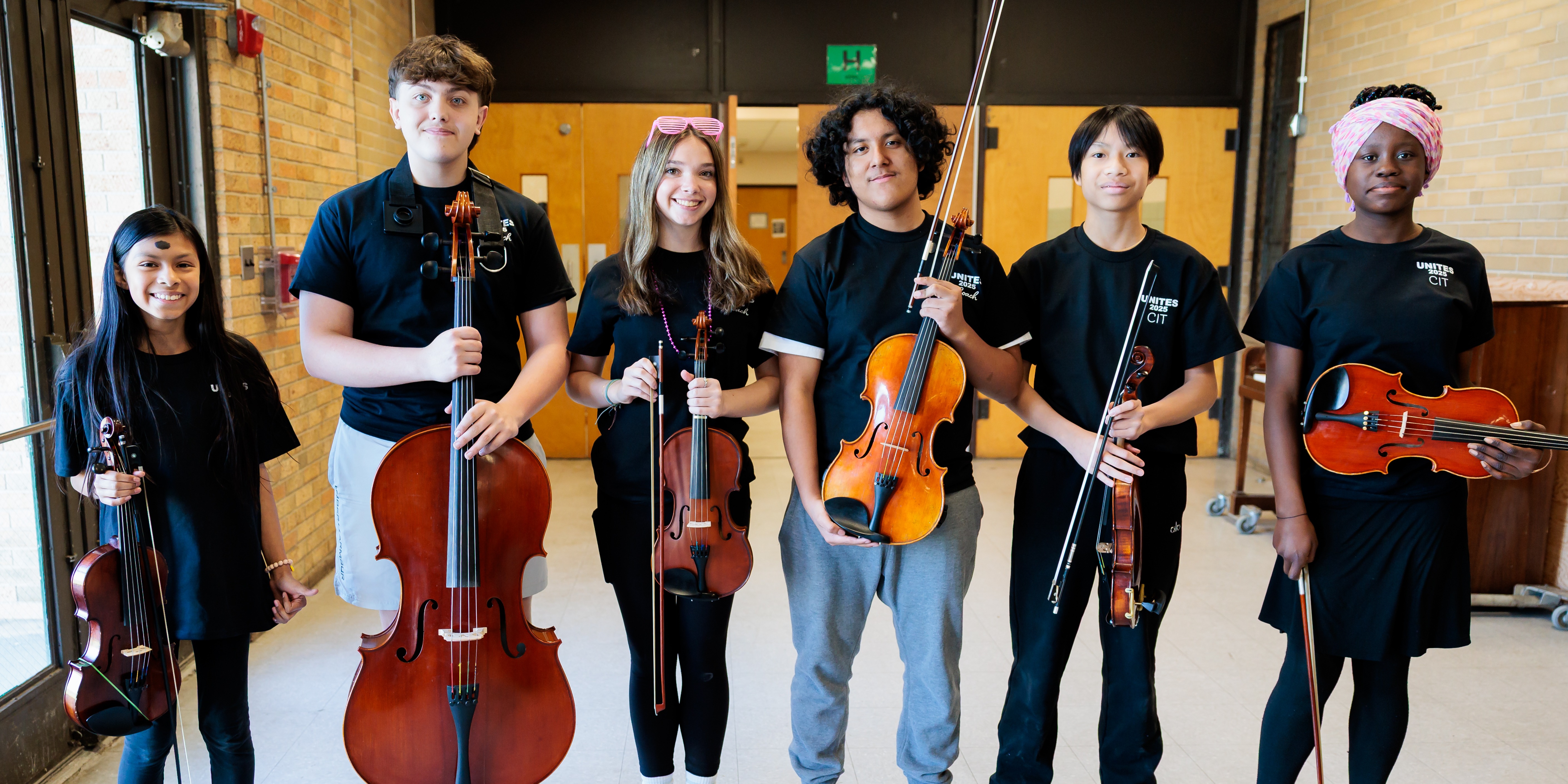 Six students from Worcester UNITES stand side-by-side while holding their instruments.