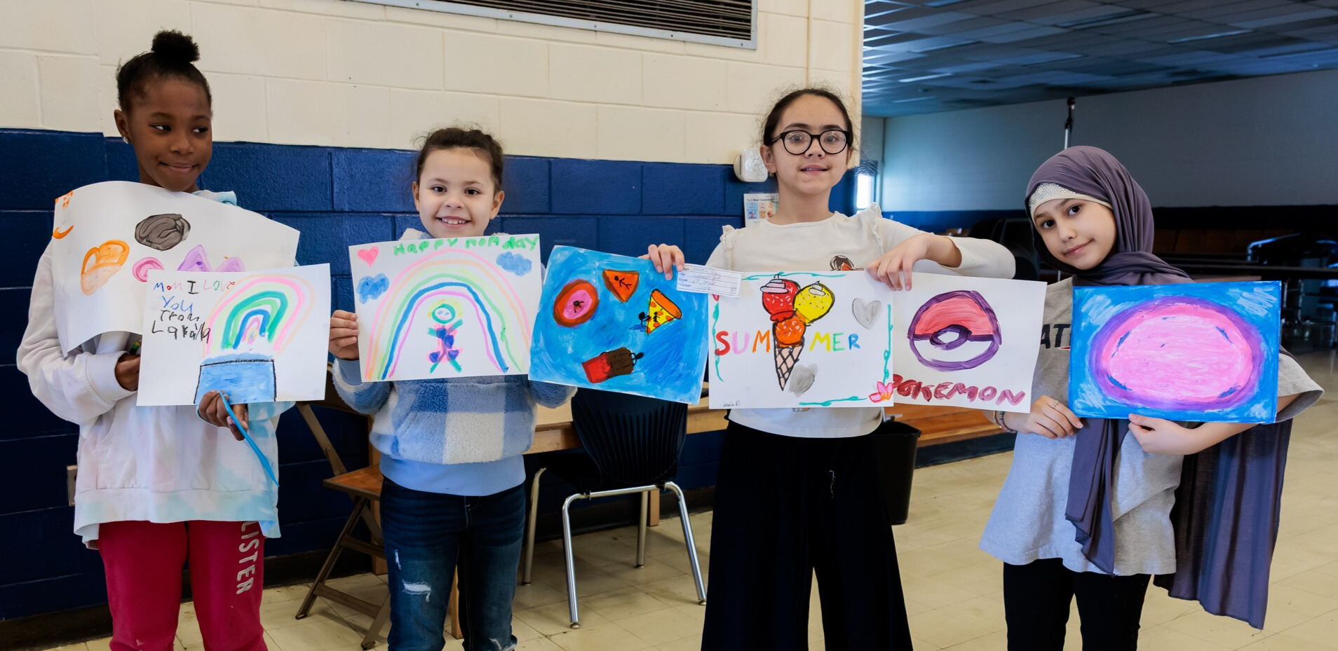 Four elementary students holding water color paintings.