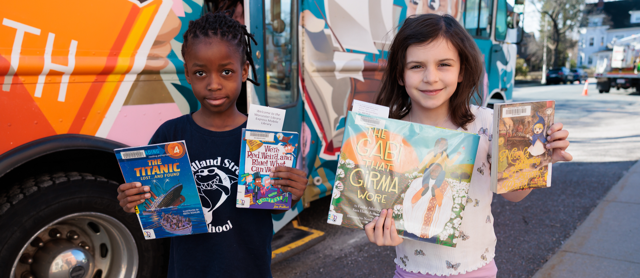 Two students hold up books.
