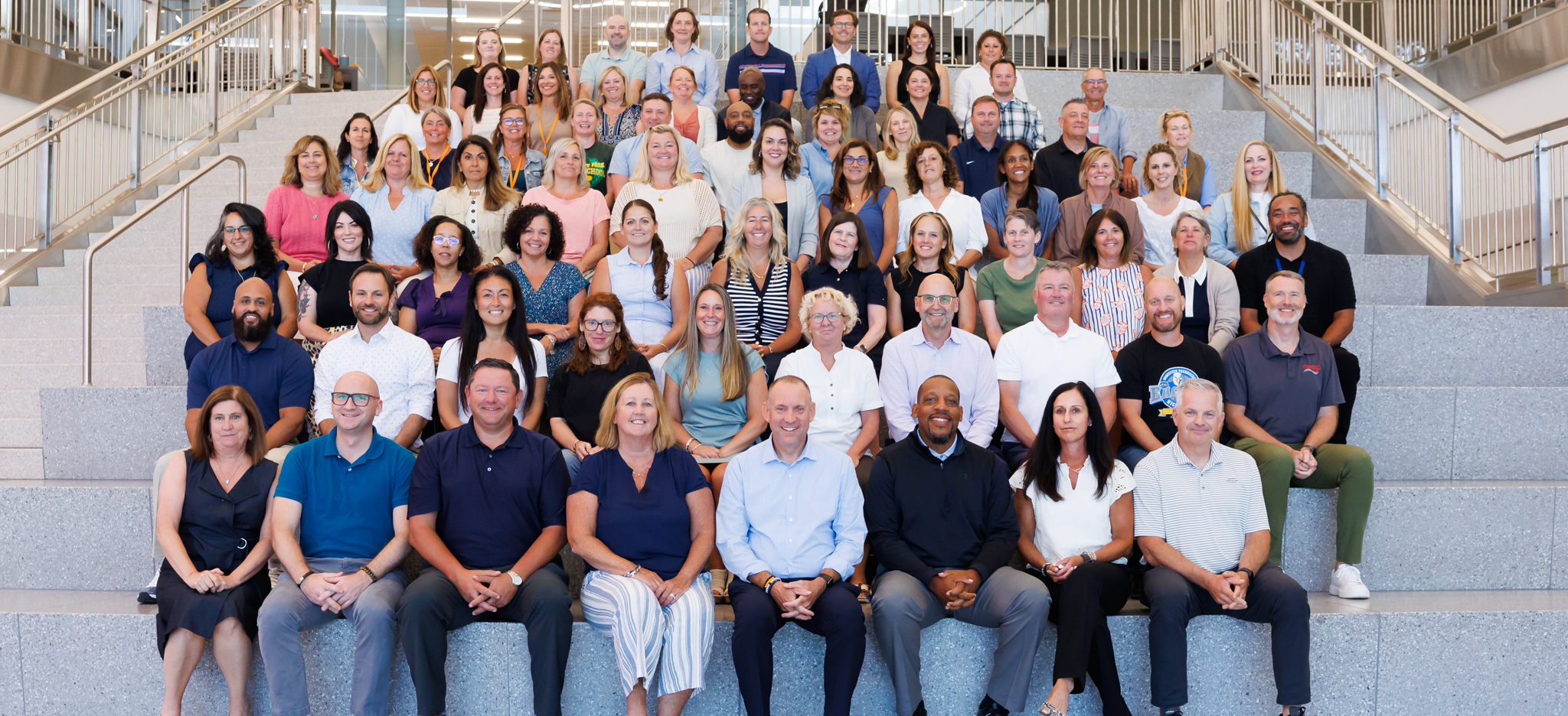 A large group of principals and administrators sit on stairs for a group photo.