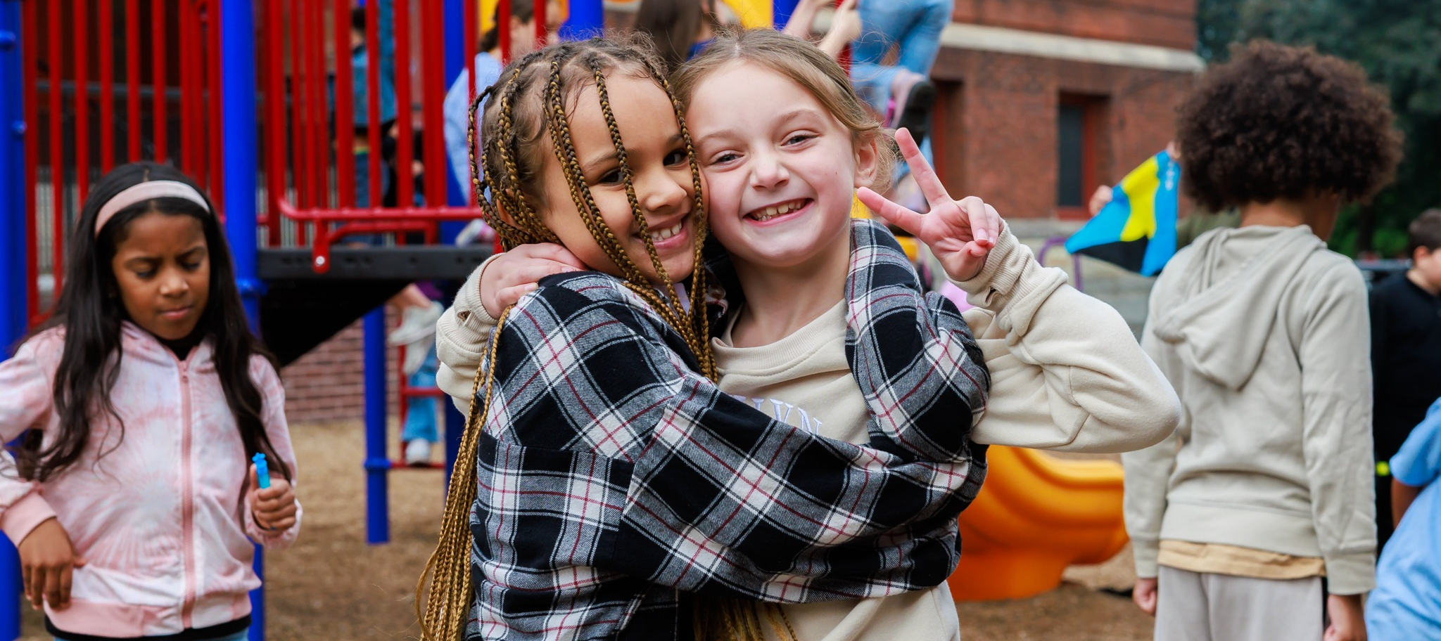 Two students smile at the camera, one giving the peace signs.