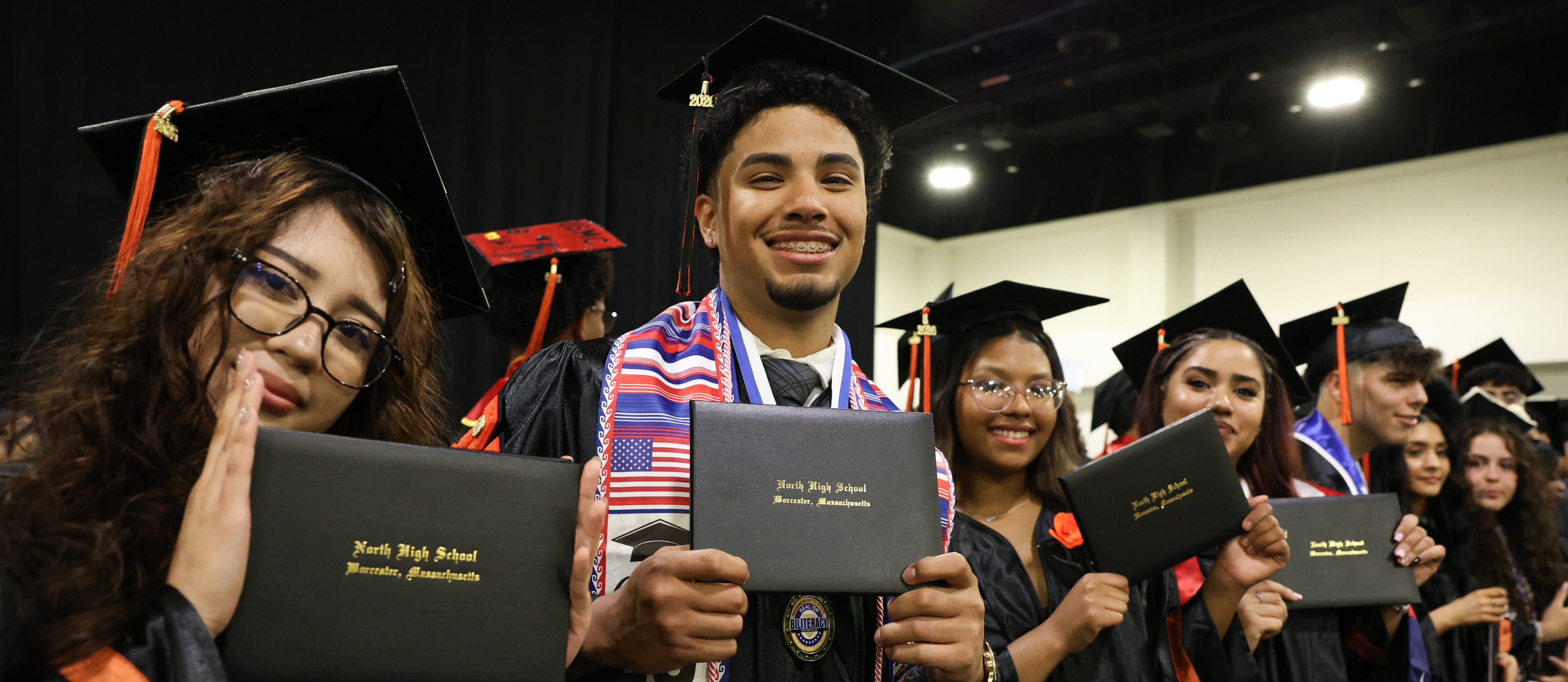 High school students show off their diplomas at graduation.
