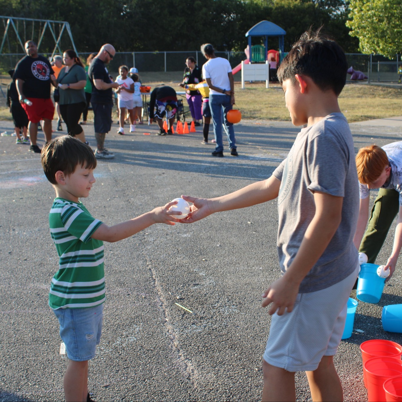 Two kids handing a ball off on a blacktop
