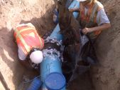 two men in reflective vests work to bury a water line