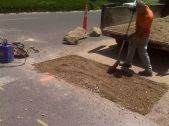 a worker prepares a hole in the road for repair