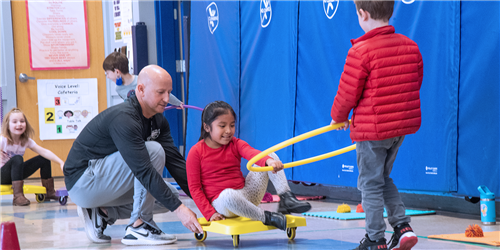 A PE teacher helps students with an activity