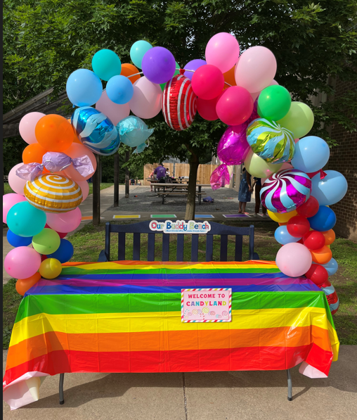 a colorful table with an arch of balloons above it