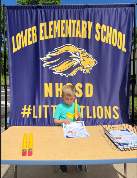 an incoming kindergarten student signs papers on a table