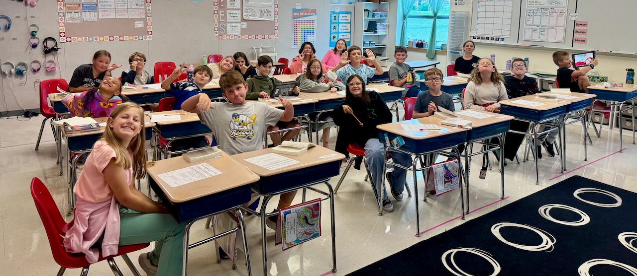 Students in classroom smiling at their desks