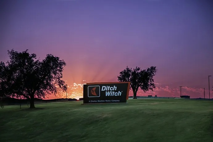 field with a sunset sky and an advertisement of ditch witch